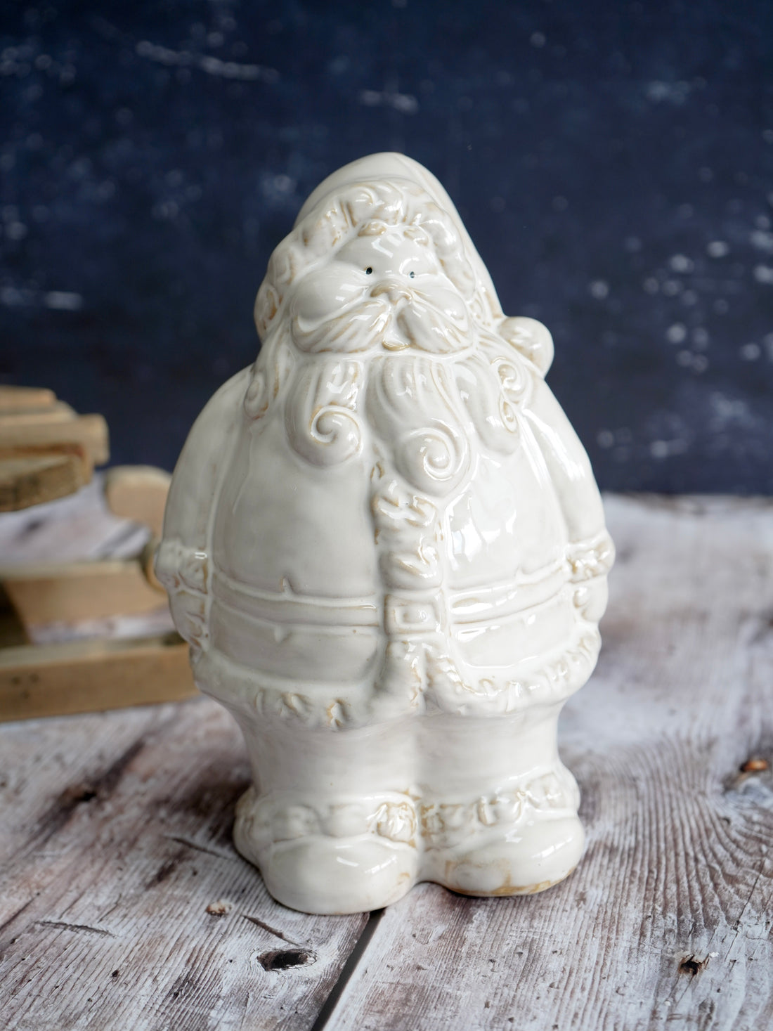 White ceramic Santa Claus figure on a wooden surface with a dark background