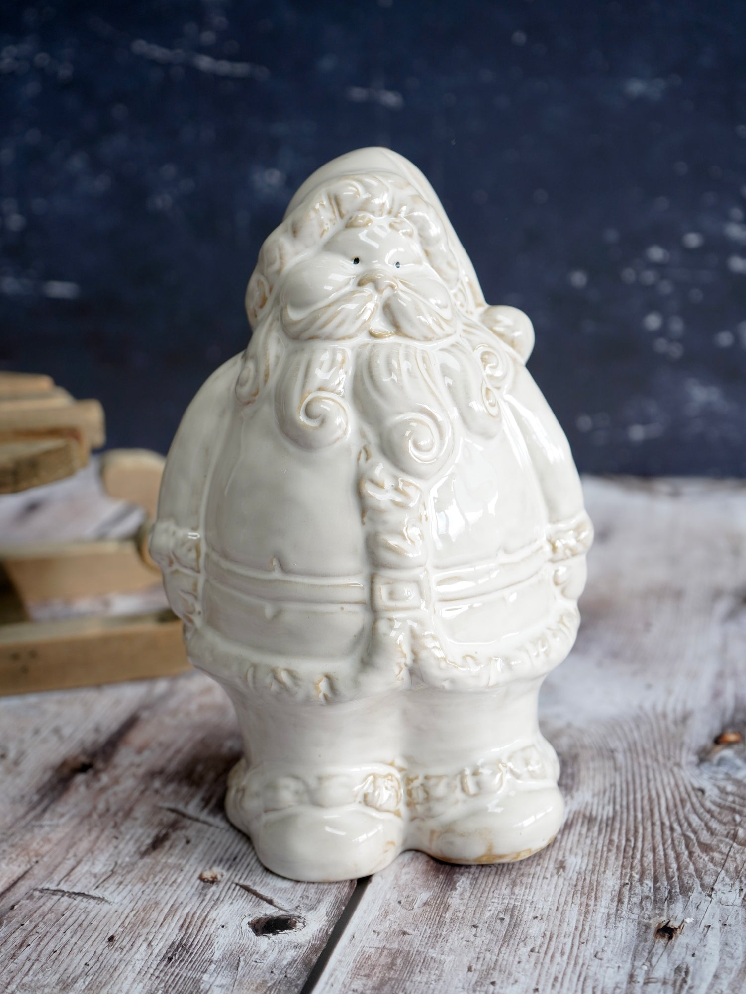 White ceramic Santa Claus figure on a wooden surface with a dark background