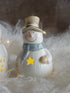 Decorative snowman figurine with a top hat and star on a soft white background