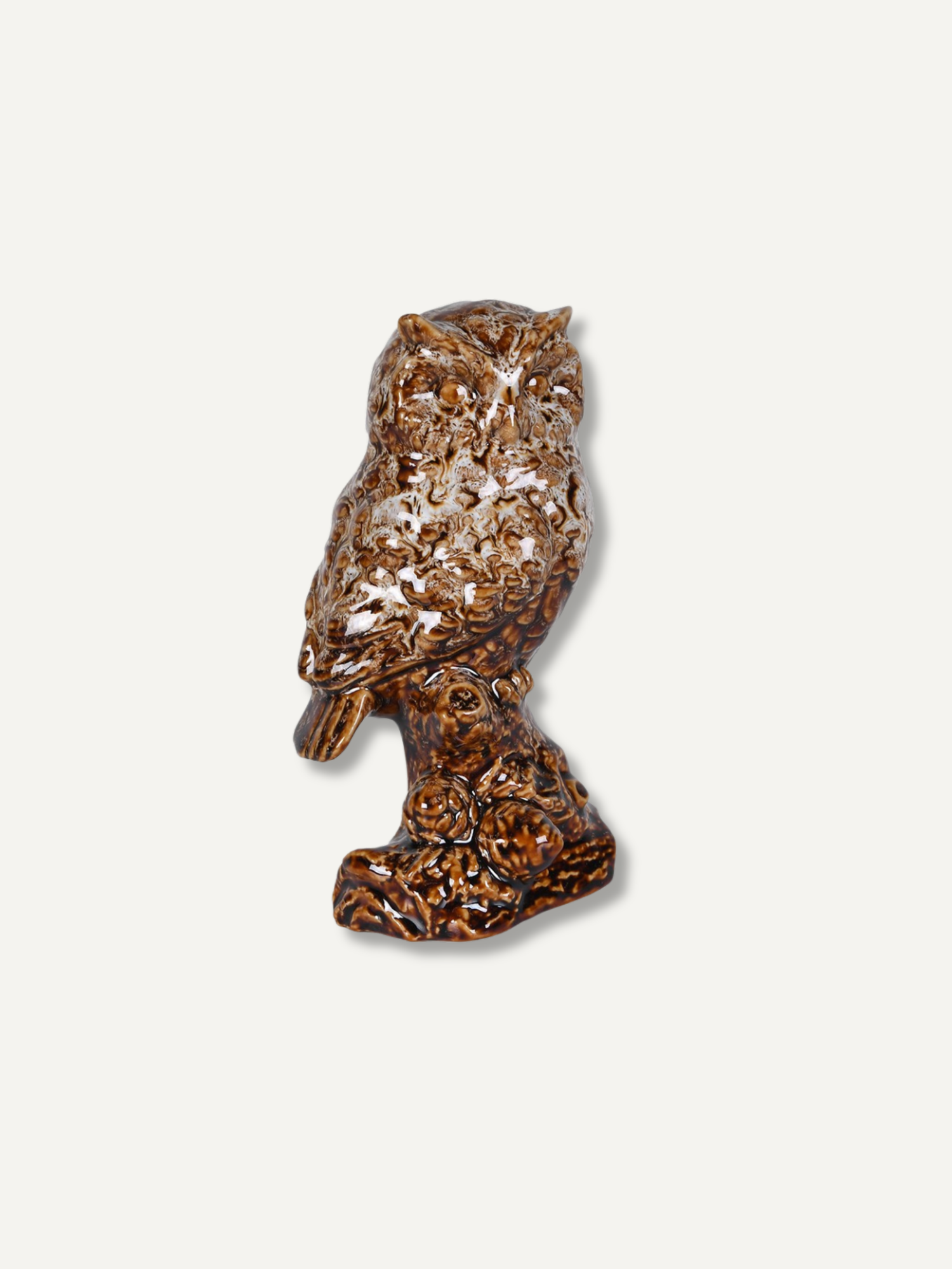 A small owl figurine in a glossy brown and amber marbled pattern, standing on a textured branch base against a light gray background.