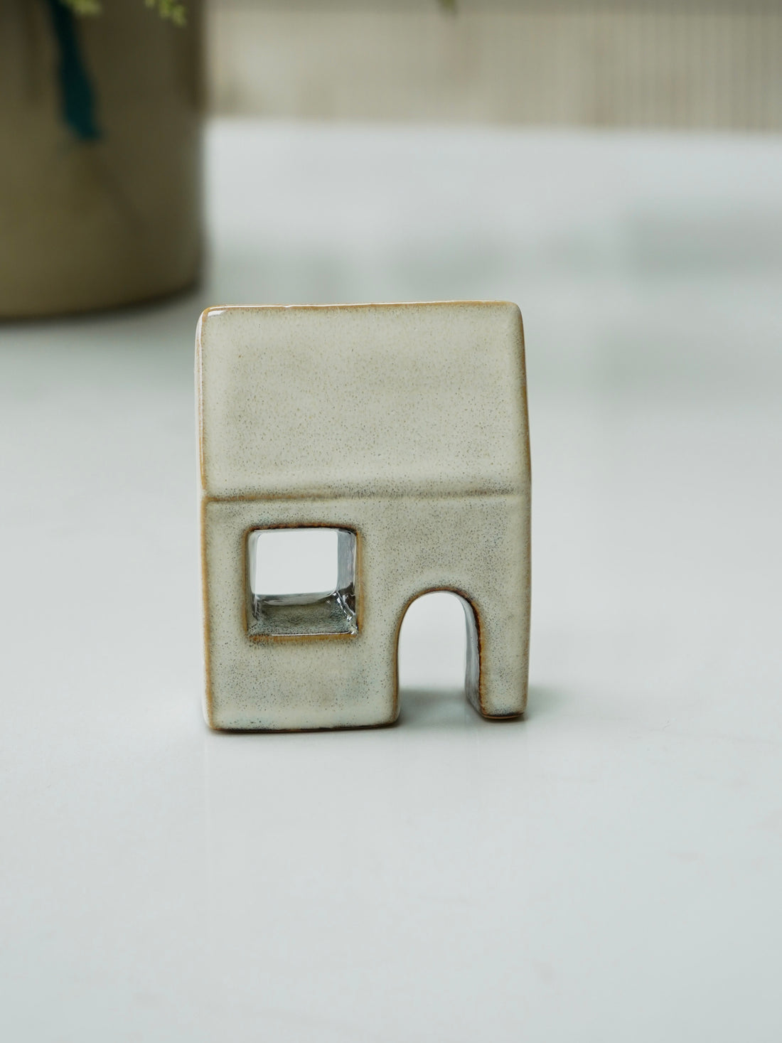 Small ceramic house-shaped object on a white surface