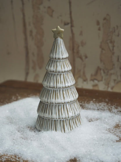 Decorative ceramic Christmas tree with a star on top, placed on a surface with a textured background.
