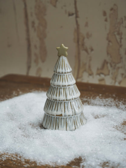 Decorative Christmas tree figurine with a star on top, placed on a snowy surface.