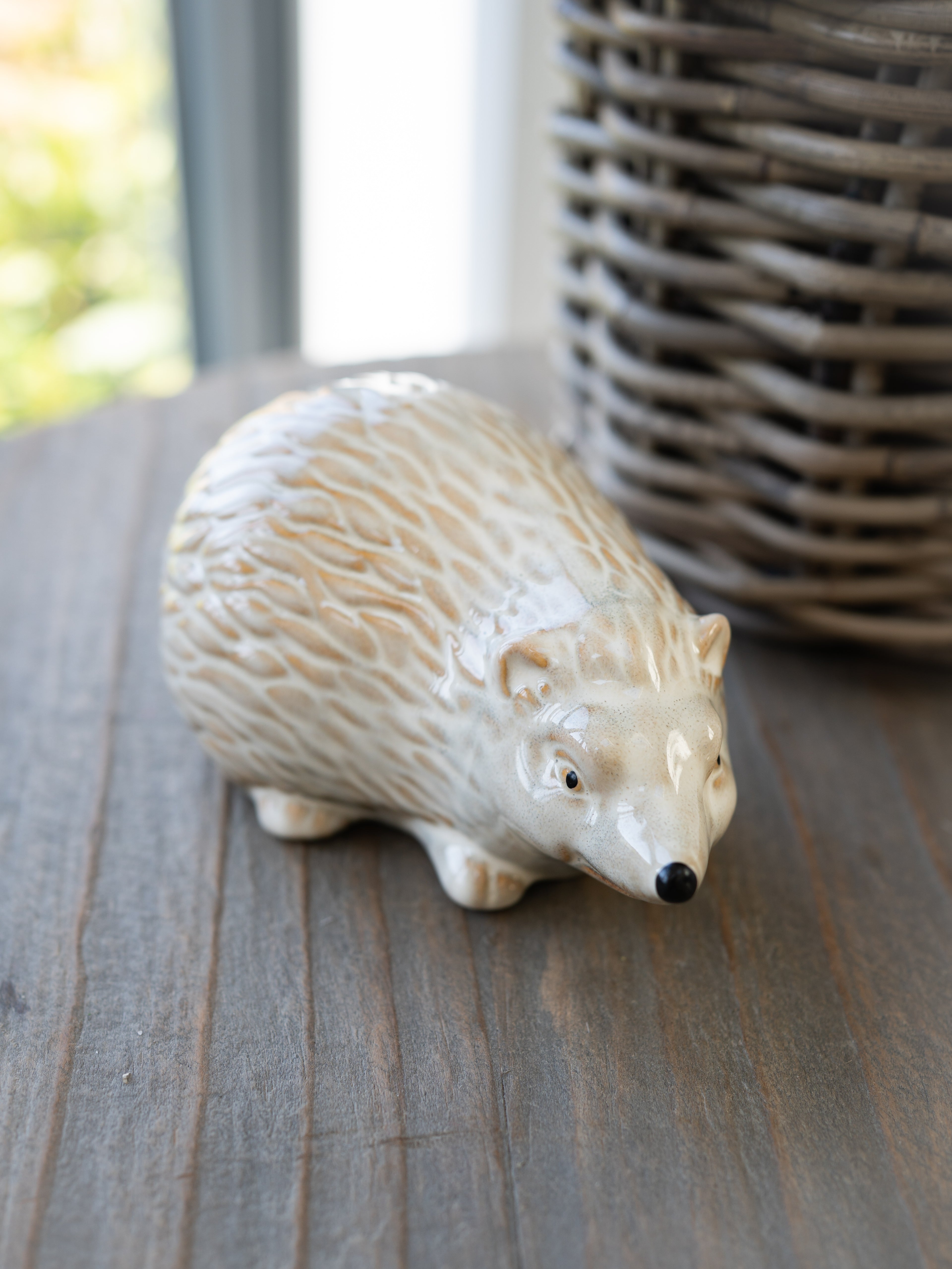 White ceramic hedgehog figurine on a wooden surface with a blurred background