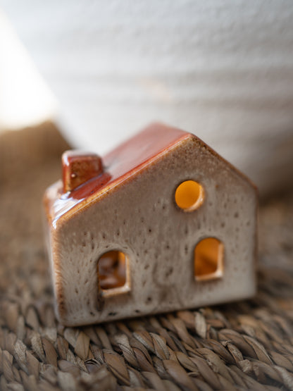 Small ceramic house-shaped object on a woven surface