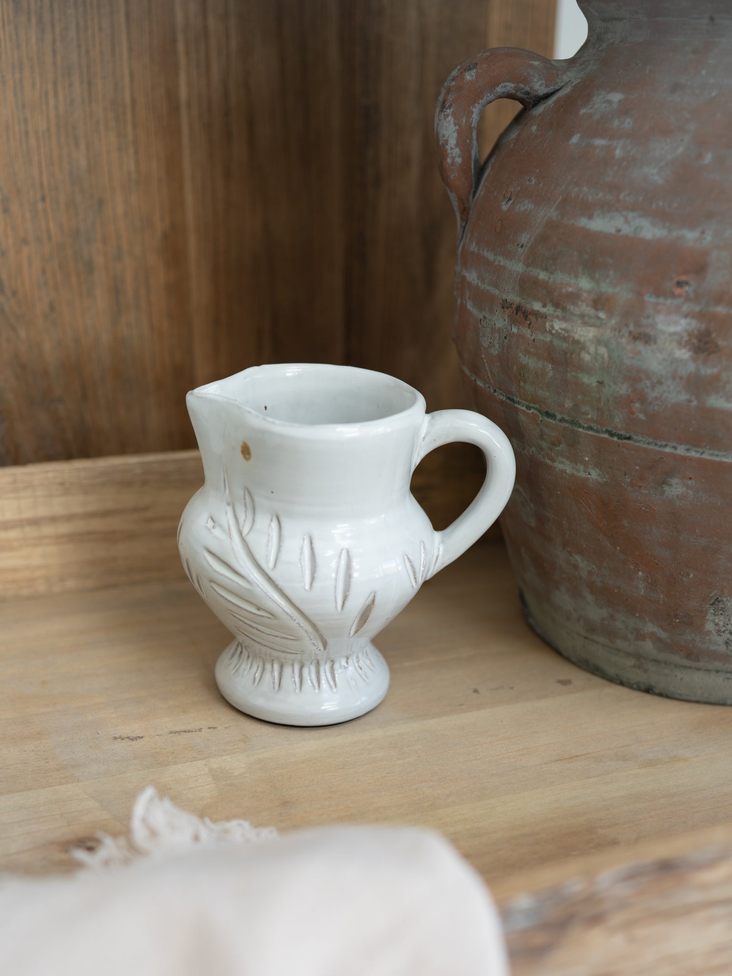 White ceramic White Leaf etched jug with decorative design on a wooden surface