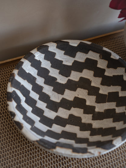 Black and white patterned ceramic decorative bowl on a textured surface
