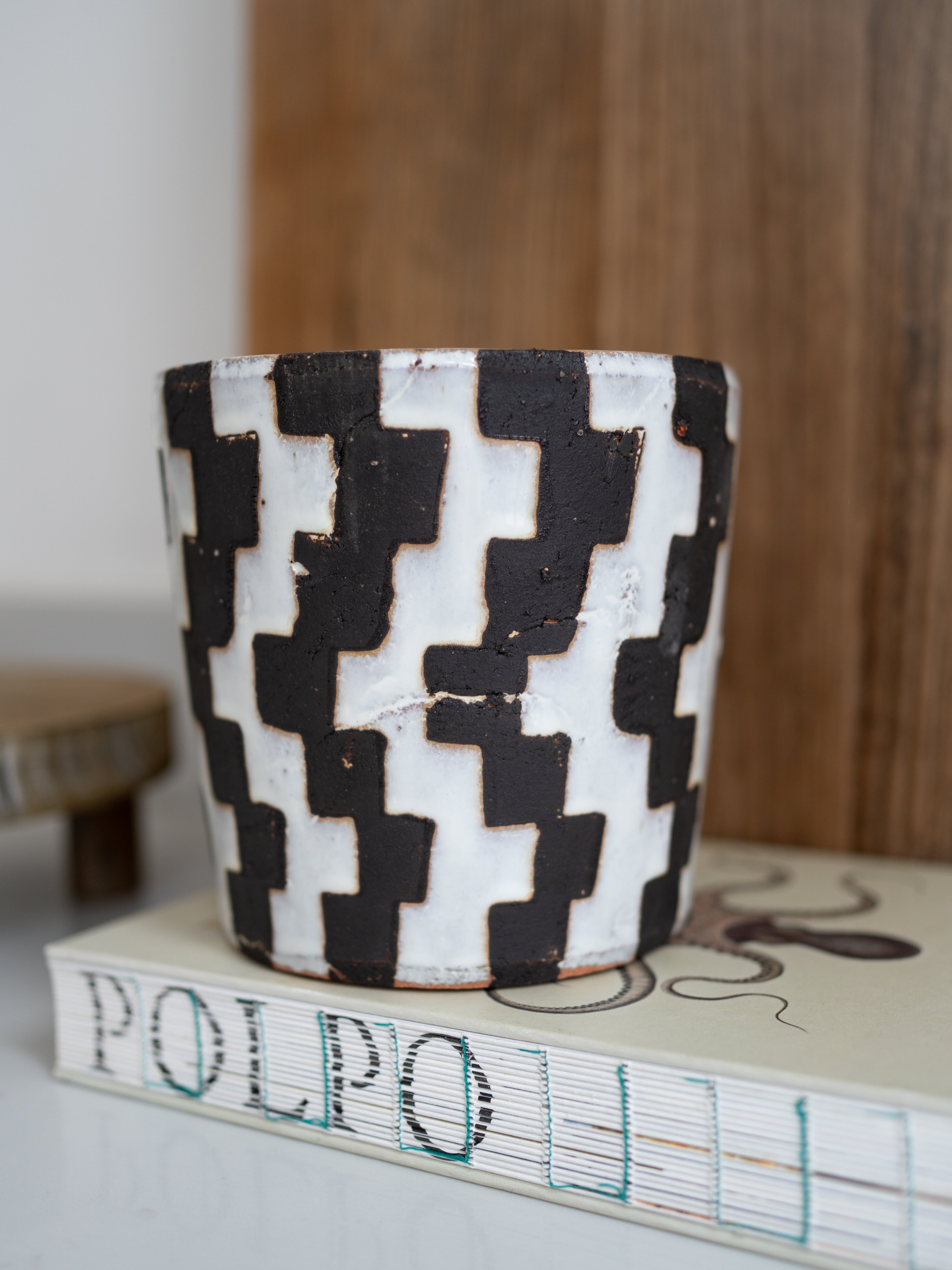 Ceramic pot with black and white geometric pattern on a book