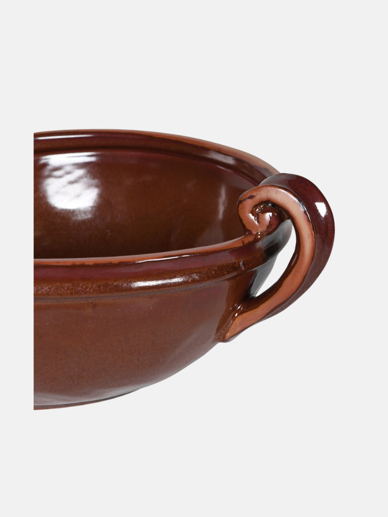 Brown ceramic bowl with handle on a white background