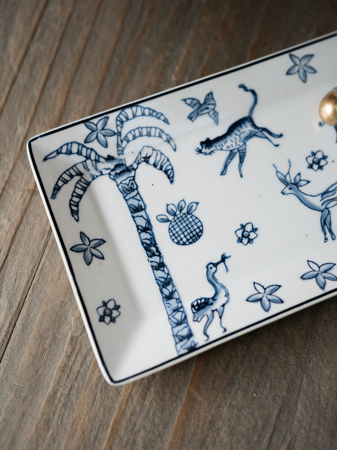 Decorative ceramic trinket tray with blue animal and plant patterns on a wooden surface