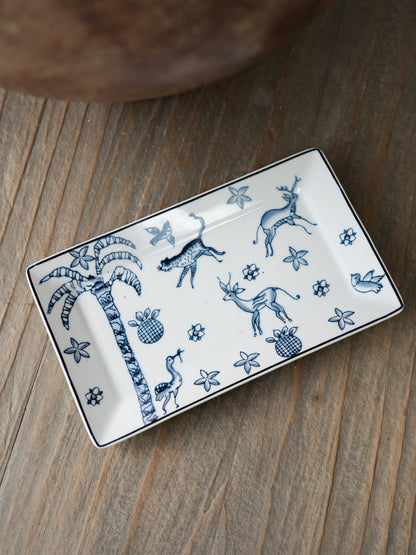 Rectangular ceramic trinket tray with blue animal and plant designs on a wooden surface