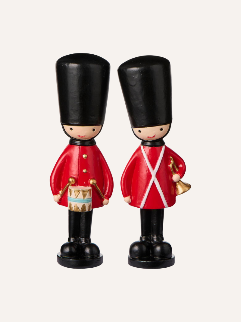 Two toy christmas figures of British guards in red uniforms and black hats on a white background