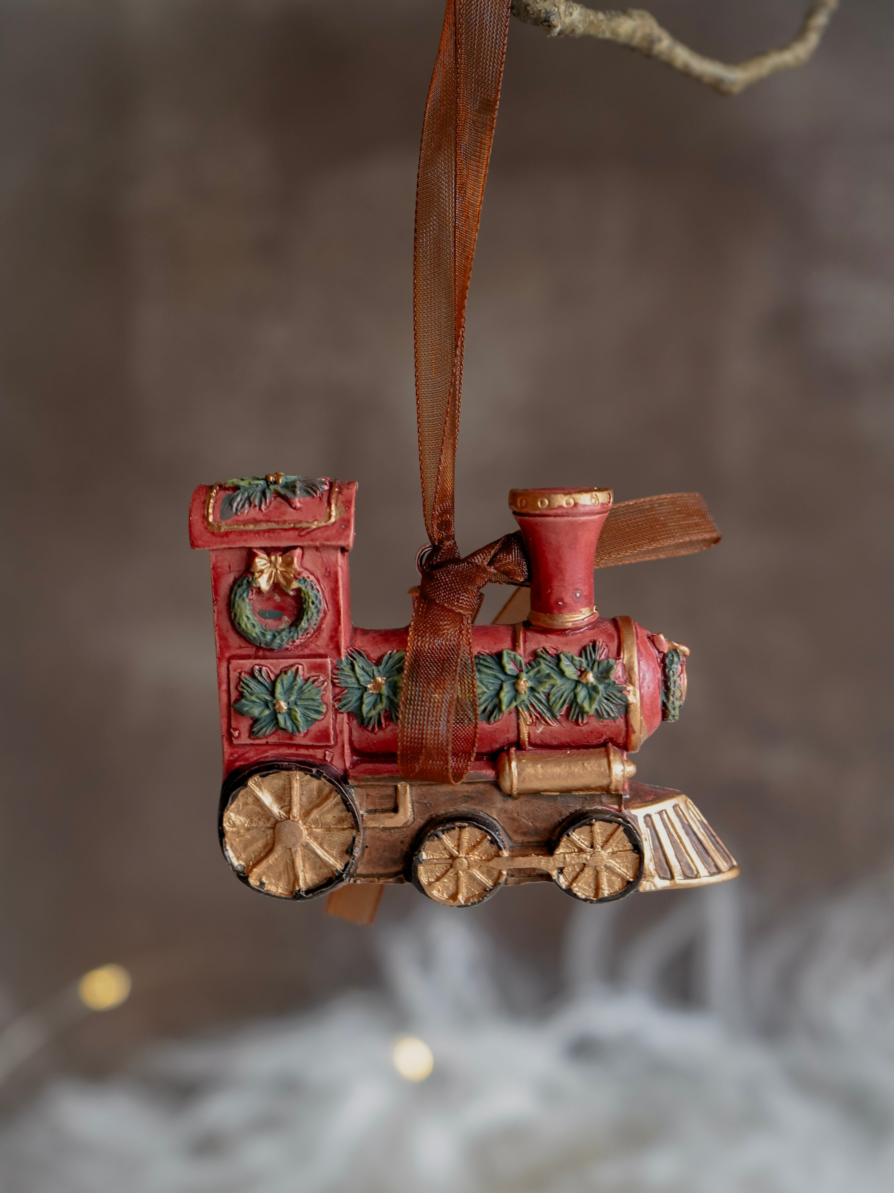Decorative train ornament with a brown ribbon against a blurred background