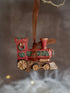 Decorative train ornament with a brown ribbon against a blurred background