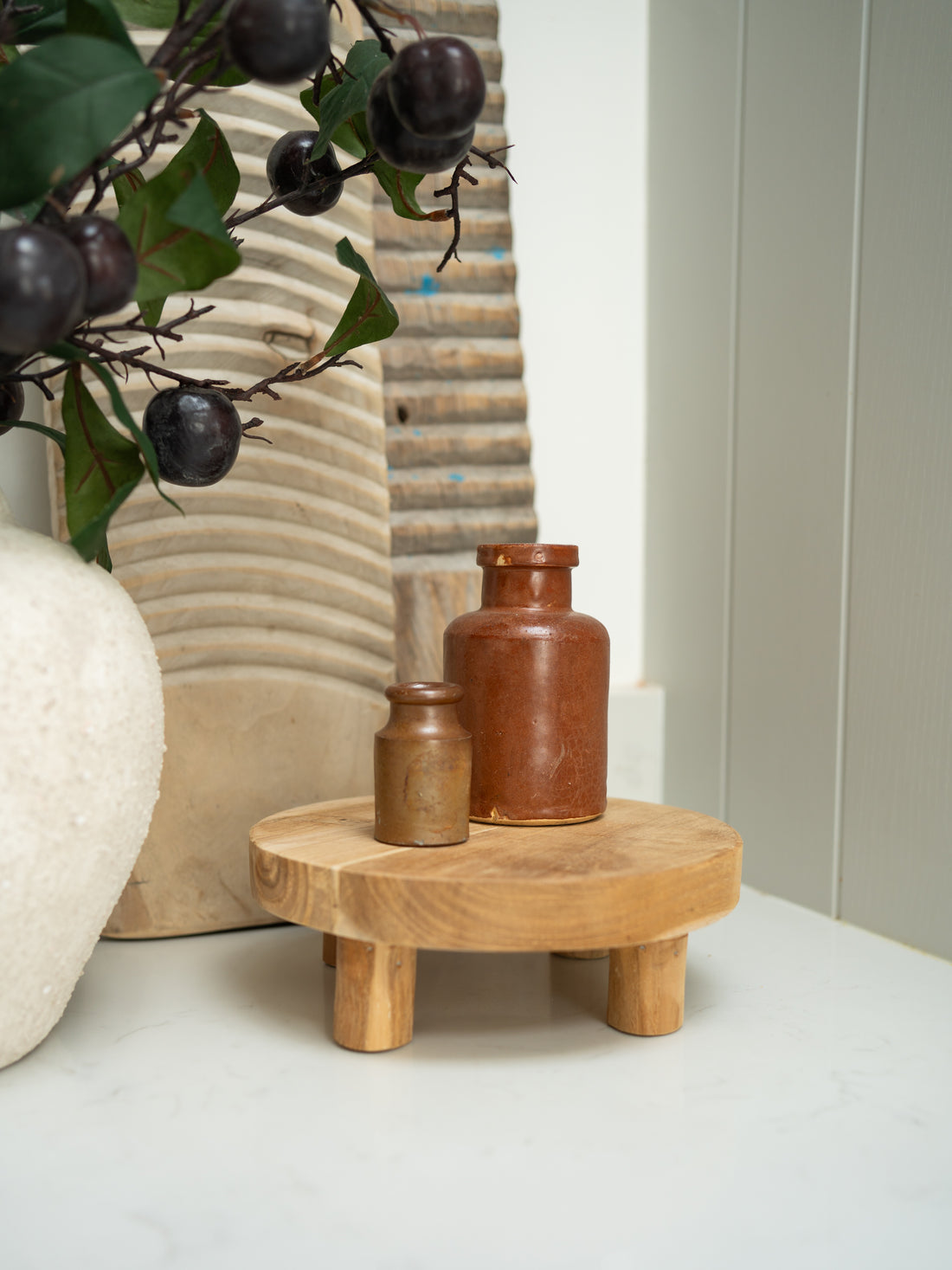 Wooden stand with two small brown bottles on a light surface, with a neutral background.