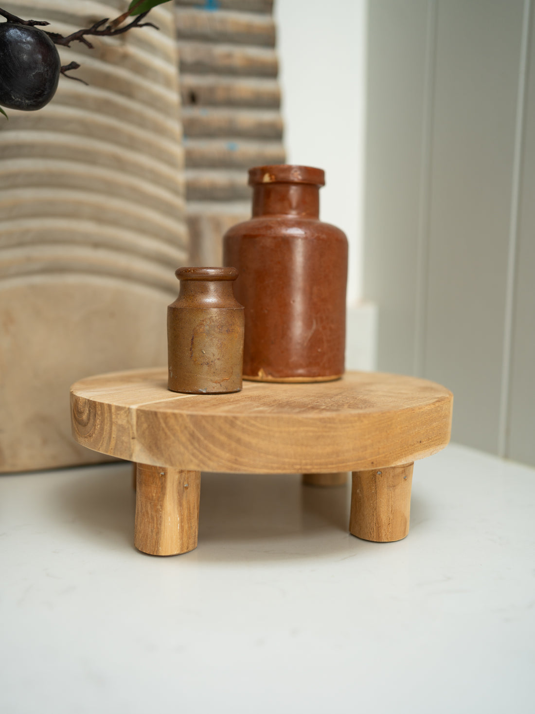 Wooden stool with two ceramic jars on a neutral background