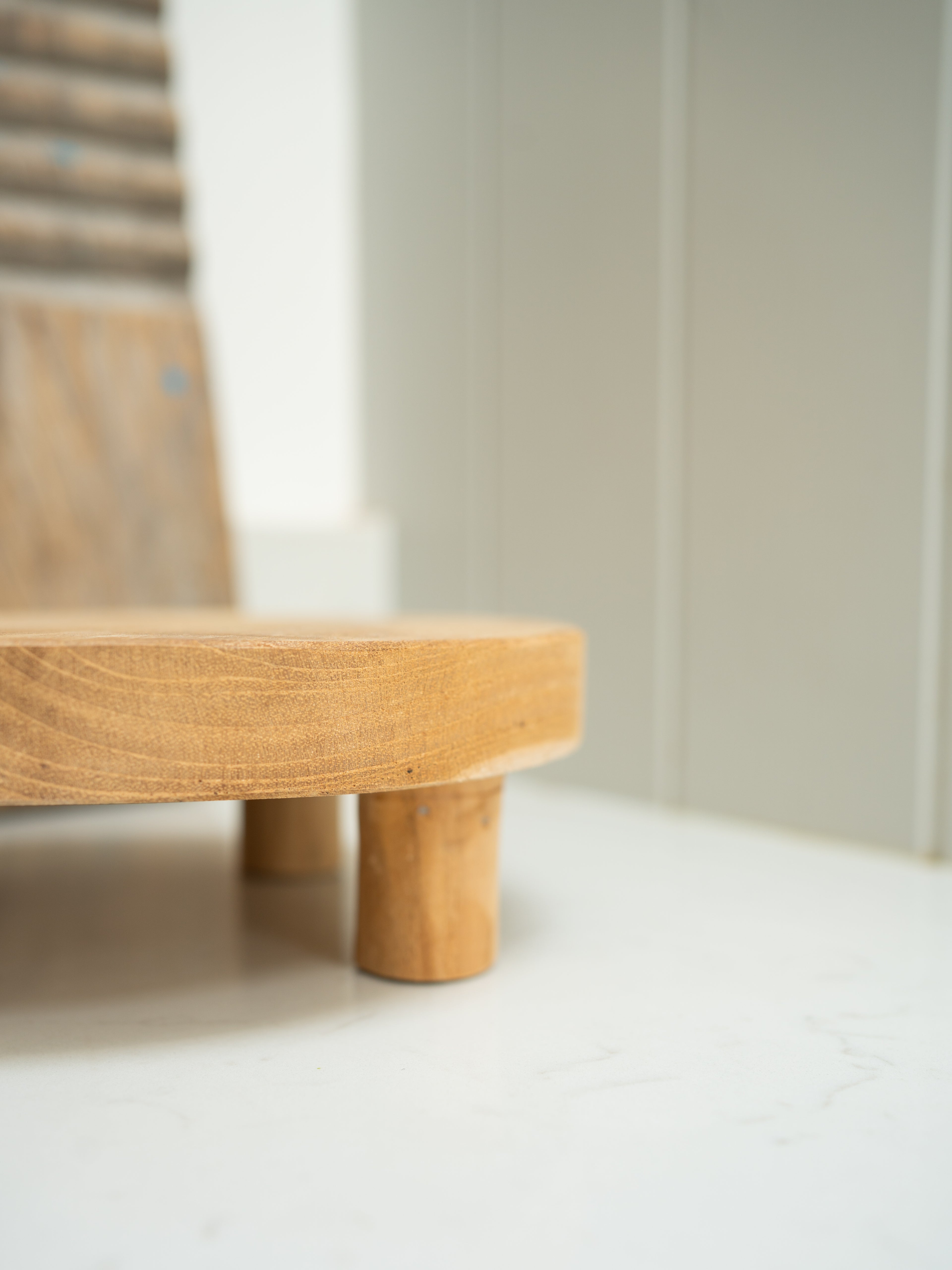 Wooden display stand with a minimalist design against a plain wall.