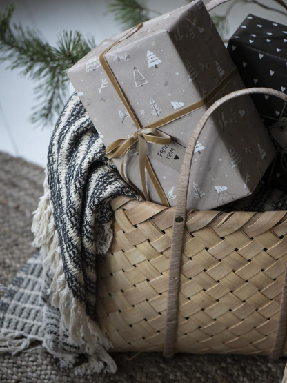 Gift basket with wrapped presents and a blanket on a textured surface