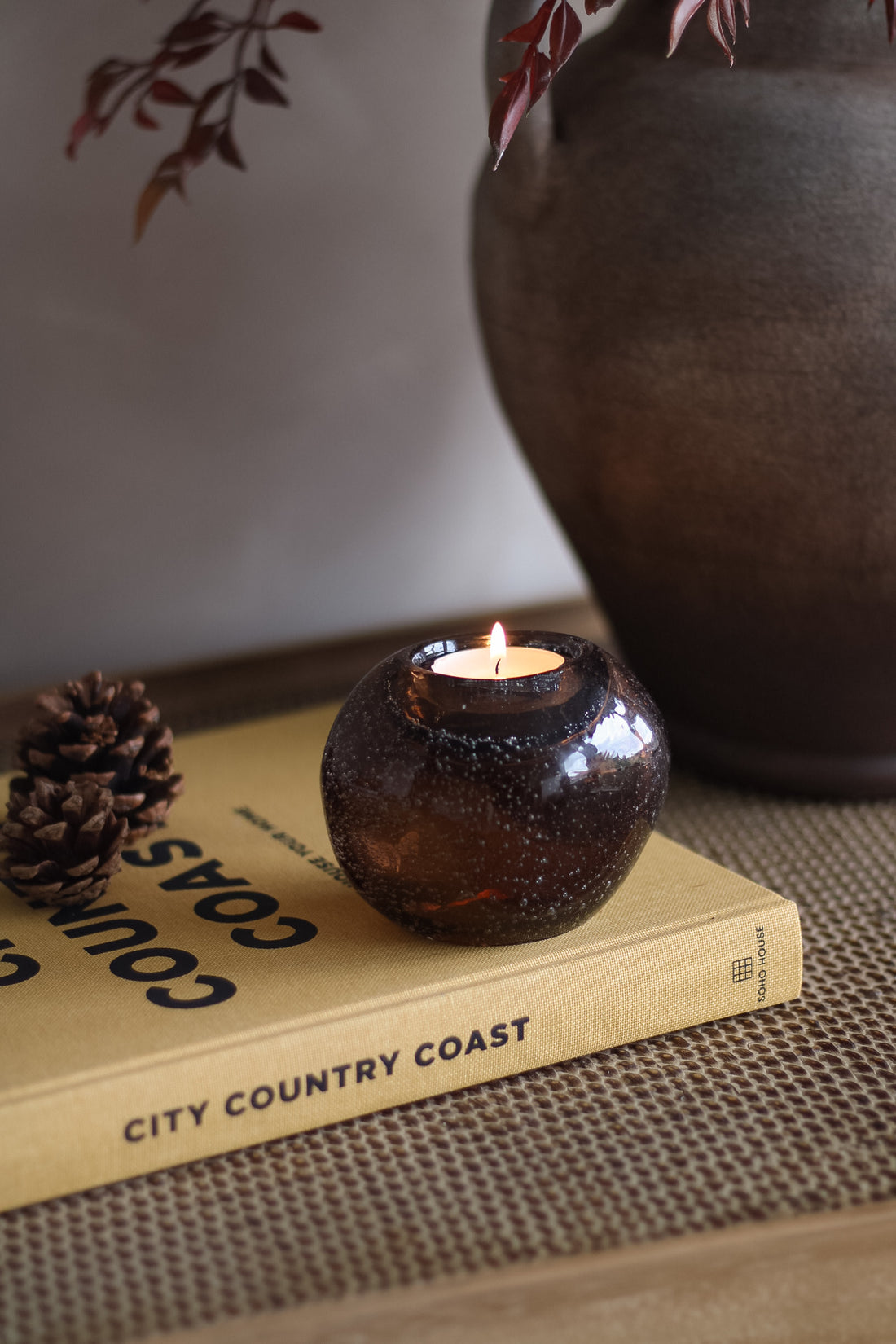 Amber glass candle holder with a lit candle on a book titled &