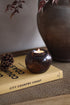 Amber glass candle holder with a lit candle on a book titled &