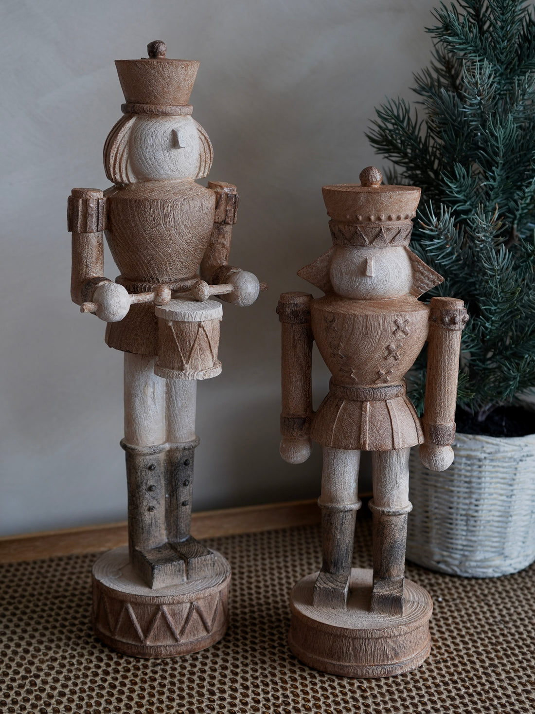 Two wooden nutcrackers on stands with a neutral background