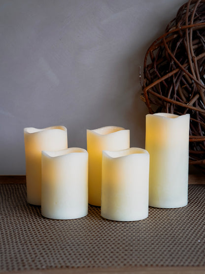 Four white candles on a textured surface with a wicker basket in the background.