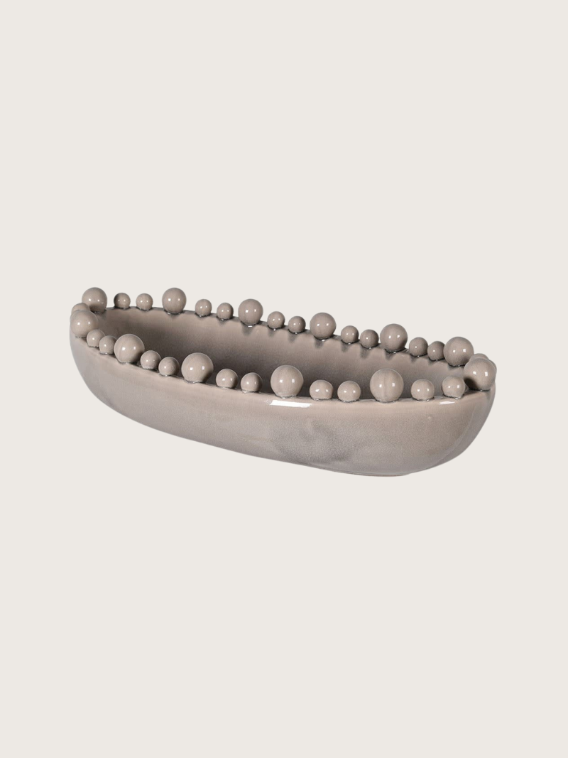 Decorative cream bowl with bobble embellishments on a light gray background