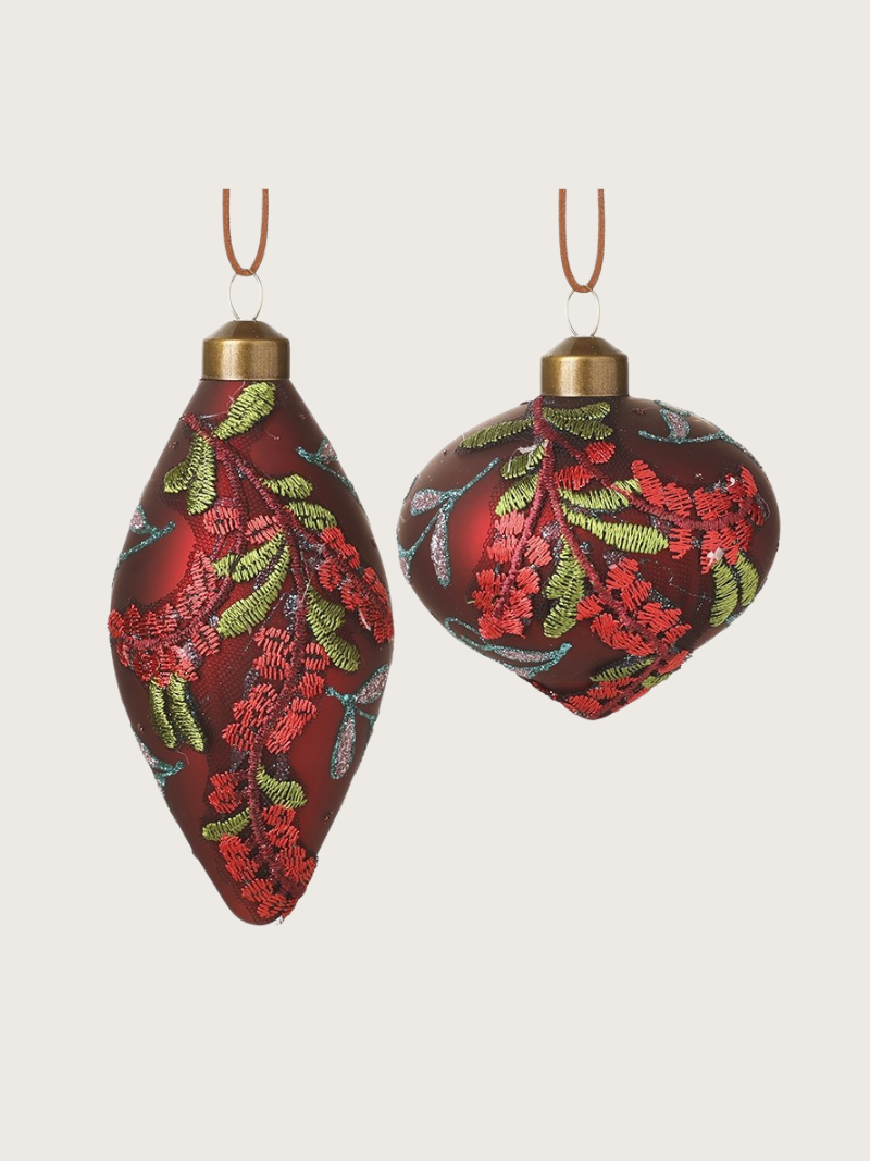 Two red floral Christmas ornaments on a beige background
