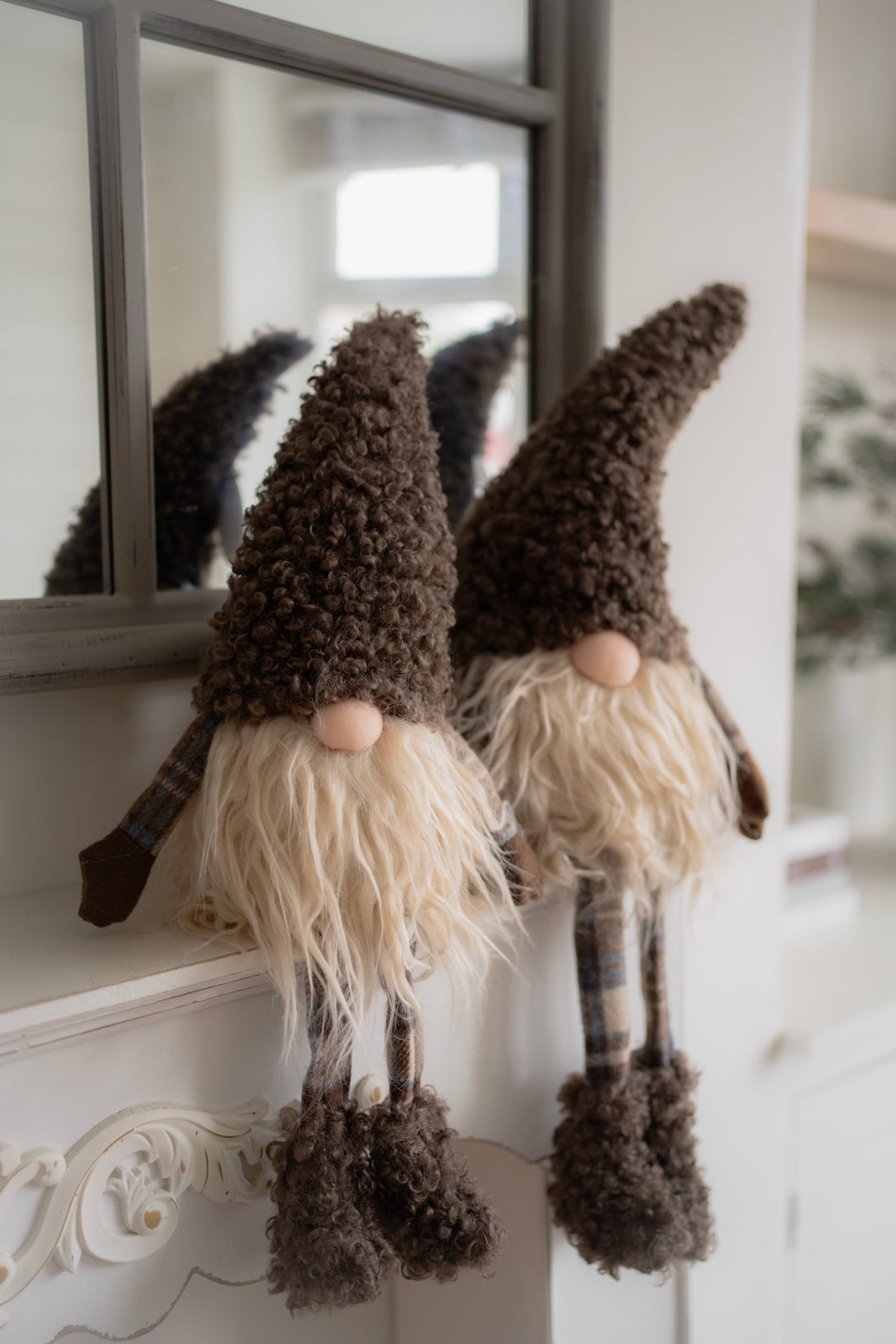 Two decorative gnomes with plaid hats and long beards on a white surface.