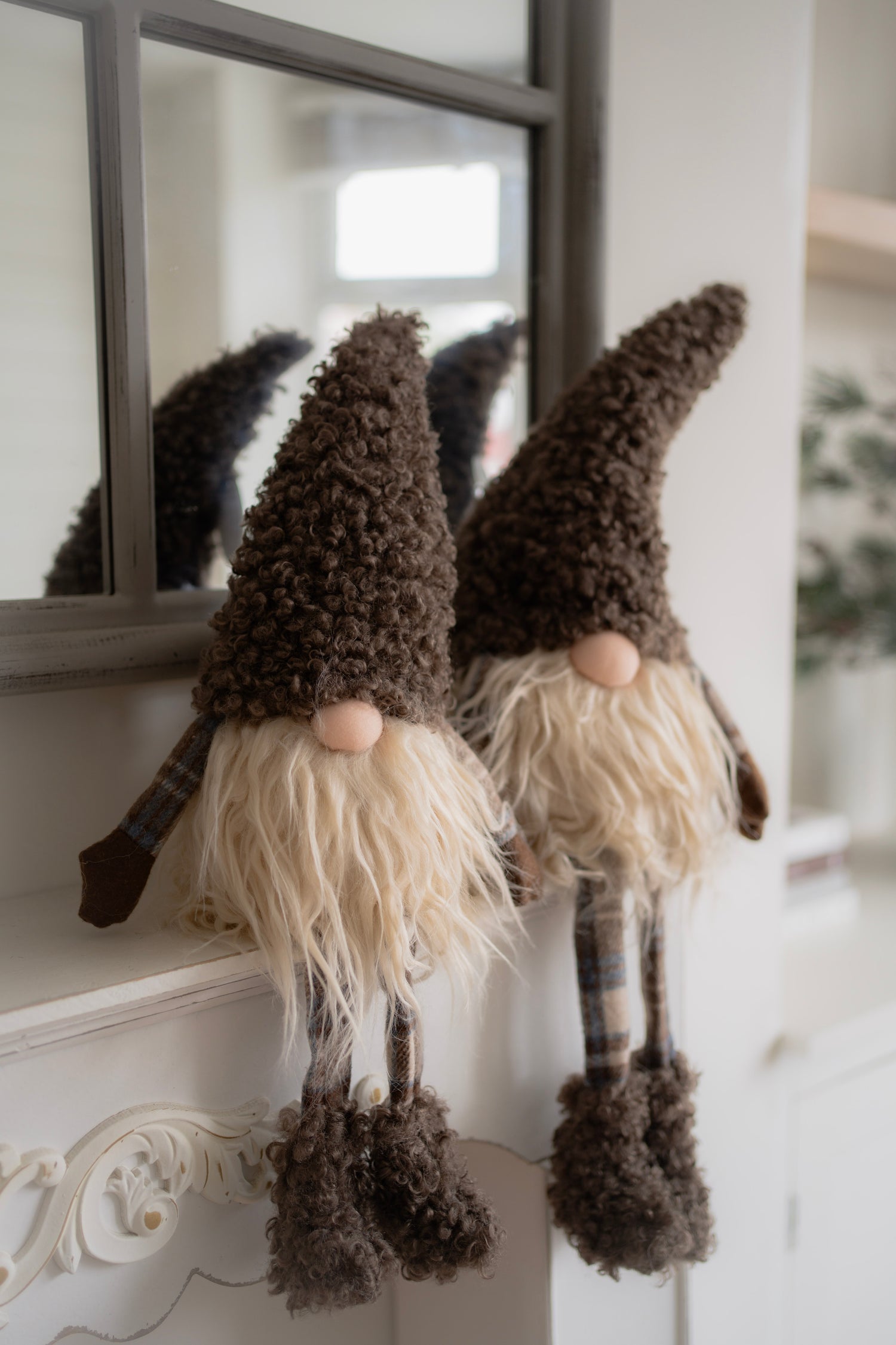 Two decorative gnomes with plaid hats and long beards on a white surface.