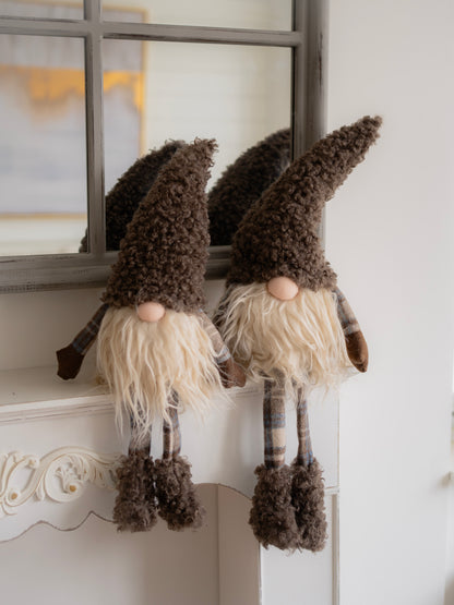 Two decorative gnomes with plaid hats and white beards hanging on a mirror.