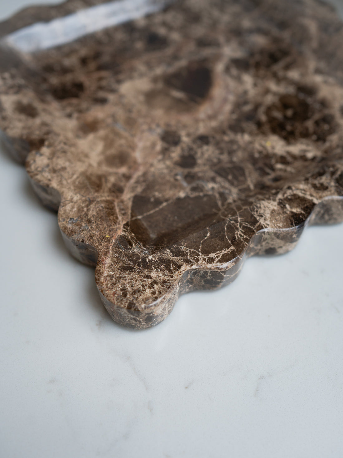 Close-up of a brown stone scalloped surface with a marble texture on a white background