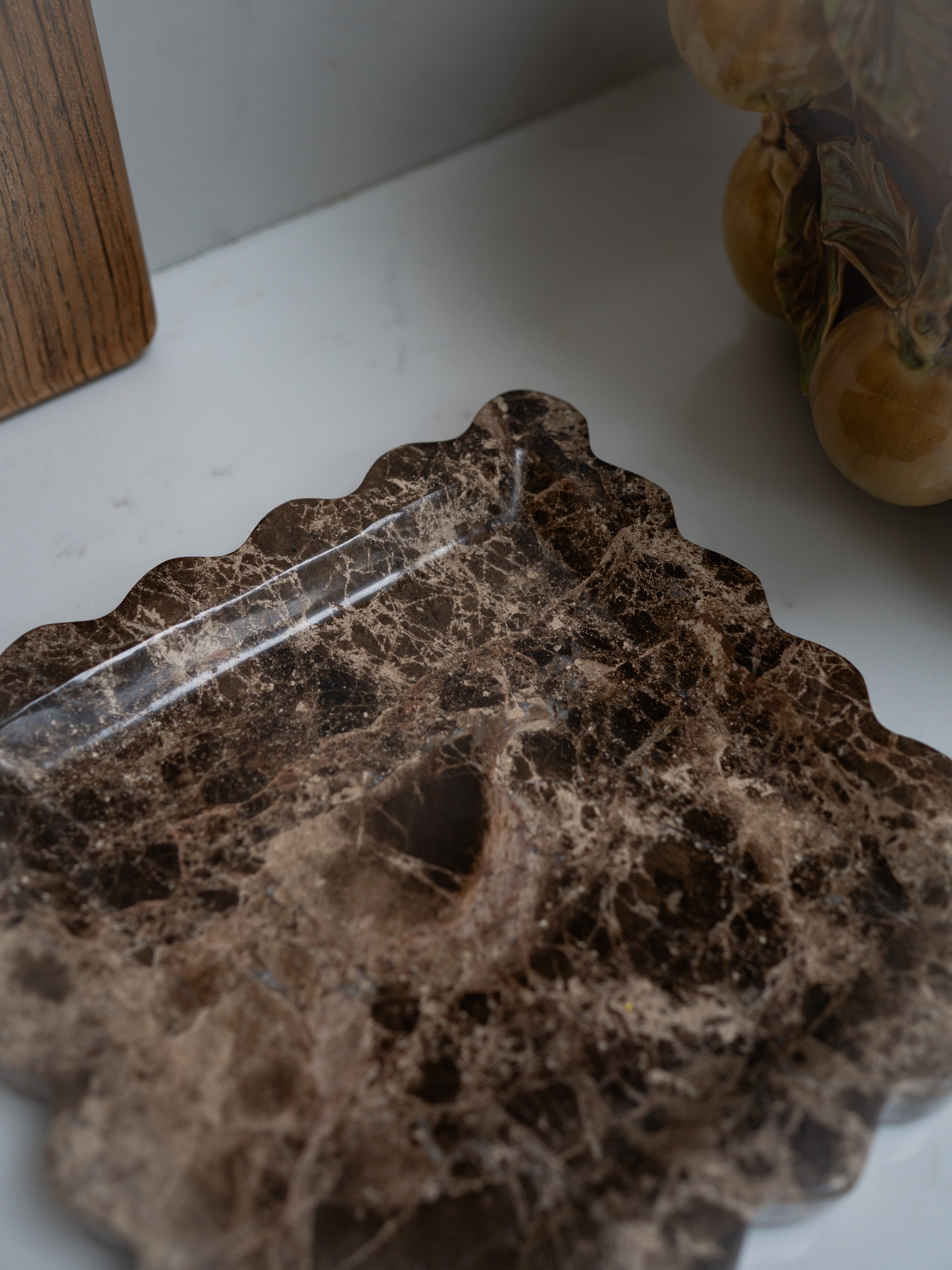 Close-up of a textured brown marble tray on a white surface