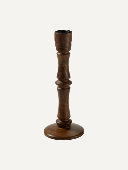 A single dark brown wooden candlestick holder with a turned, fluted shaft and a round base, shown against a plain off-white background.