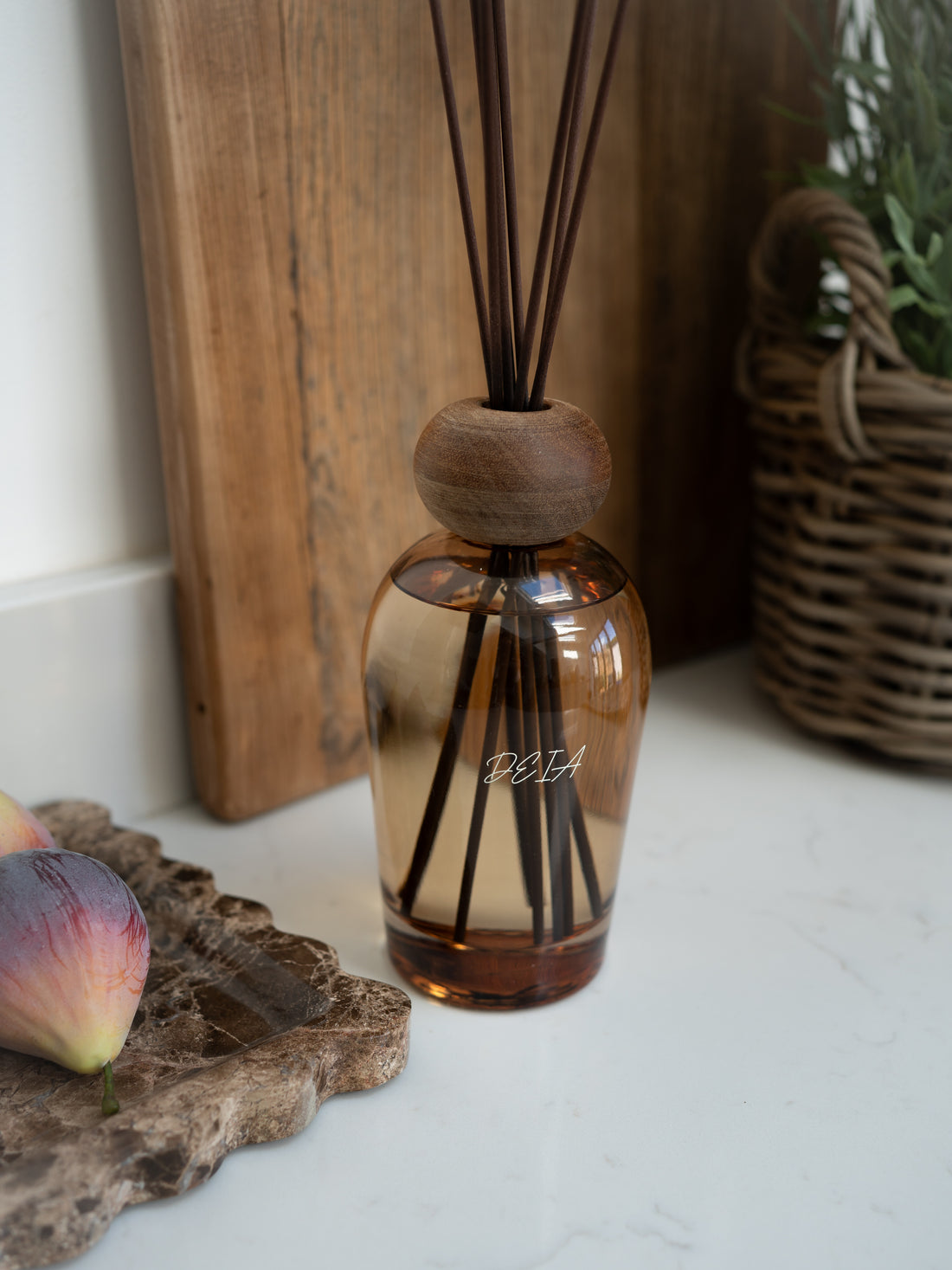 Brown diffuser bottle with wooden cap on a white surface, with &
