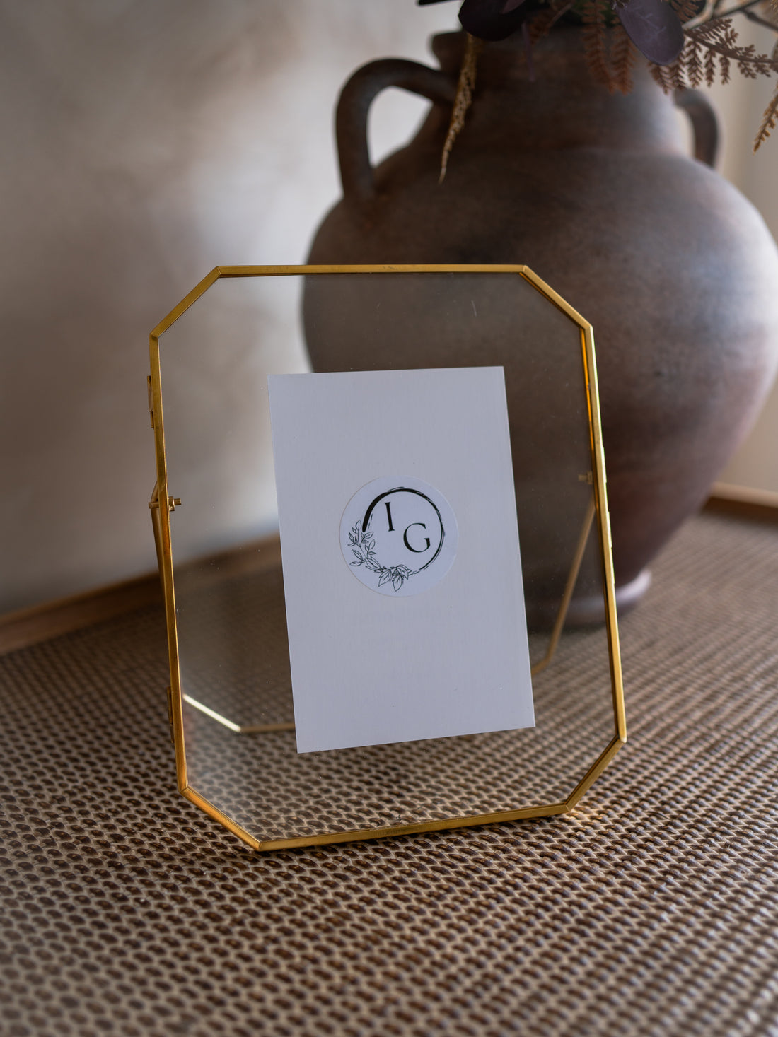 Gold geometric photo frame with a white card featuring a logo on a textured surface.