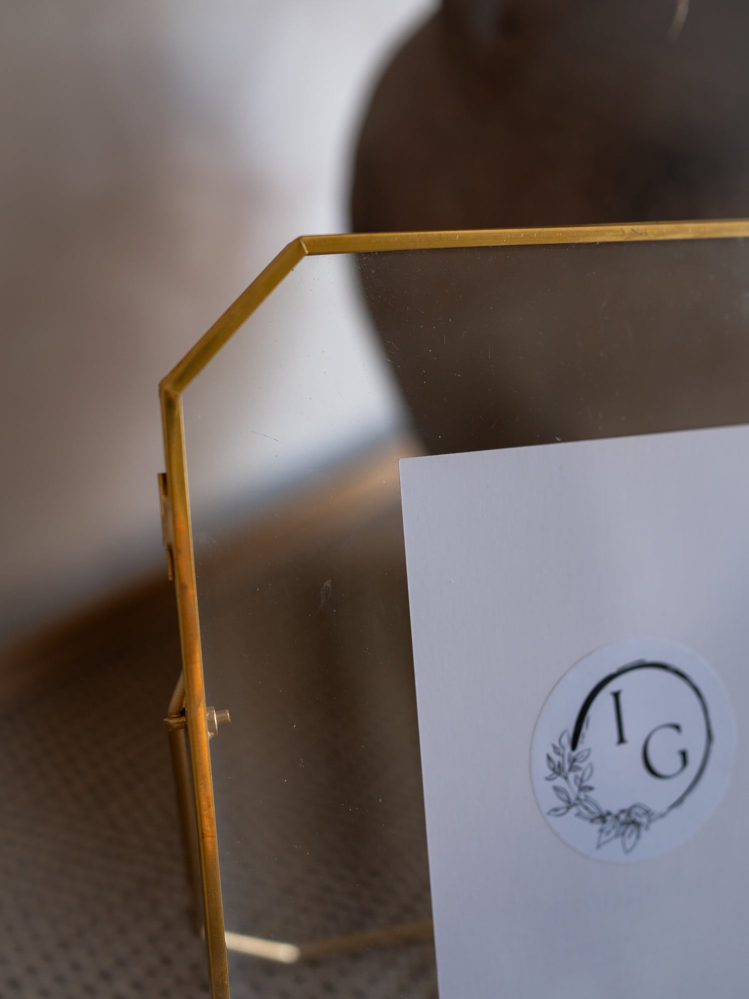 Gold metal stand holding a white card with a logo on a blurred background