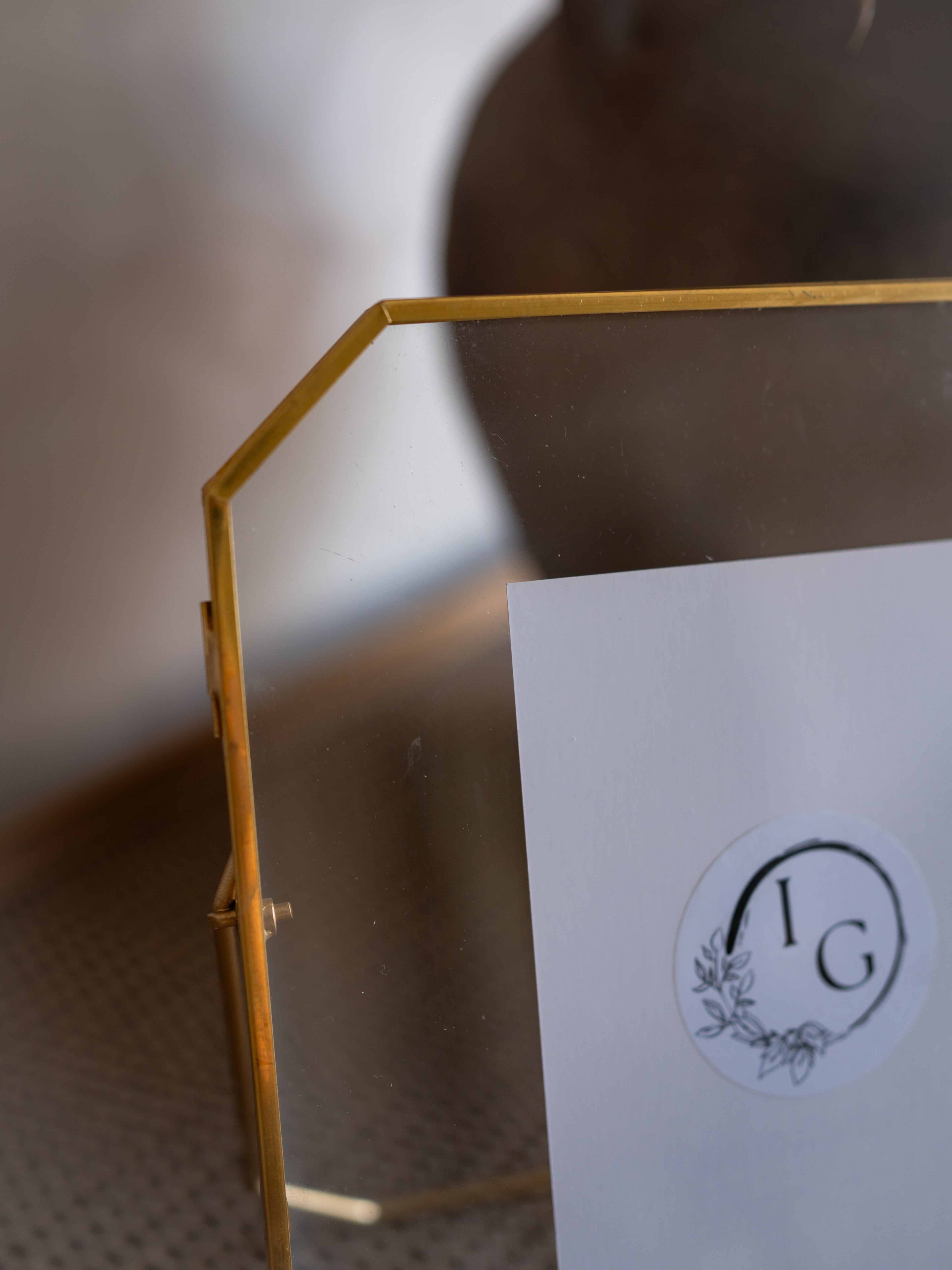 Gold metal stand holding a white card with a logo on a blurred background