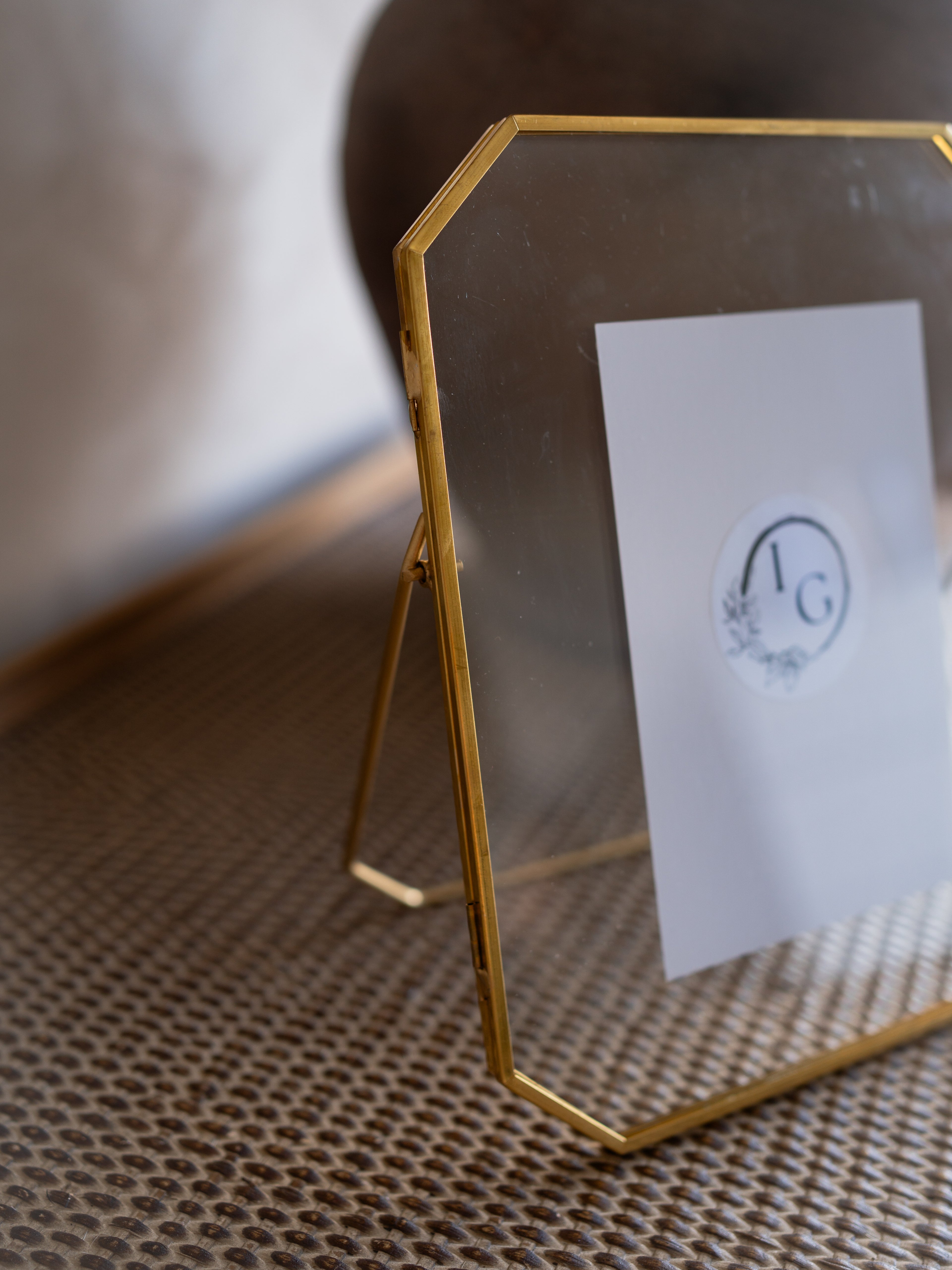 Gold photo frame with a white card featuring a logo on a textured surface