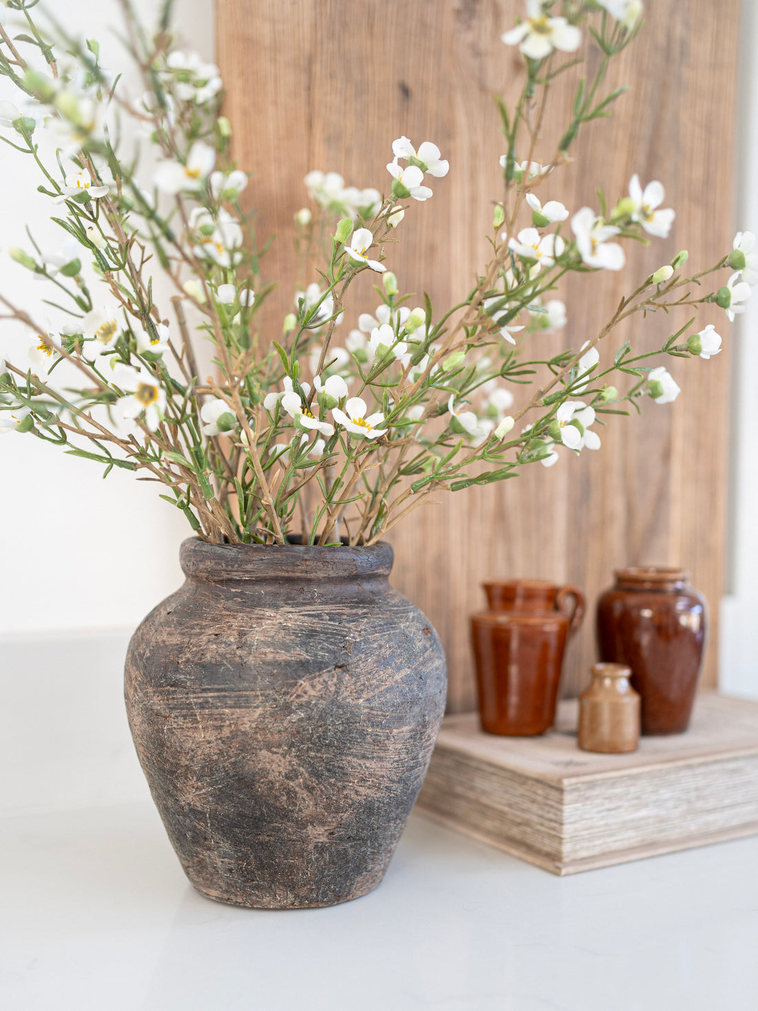 Decorative vase with white flowers on a light surface with wooden background