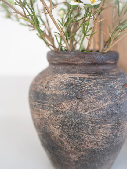 Vintage-style stone vase with small white flowers on a light background
