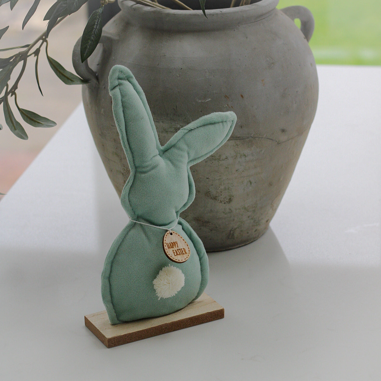 Green velvet bunny on wooden stand with happy easter tag