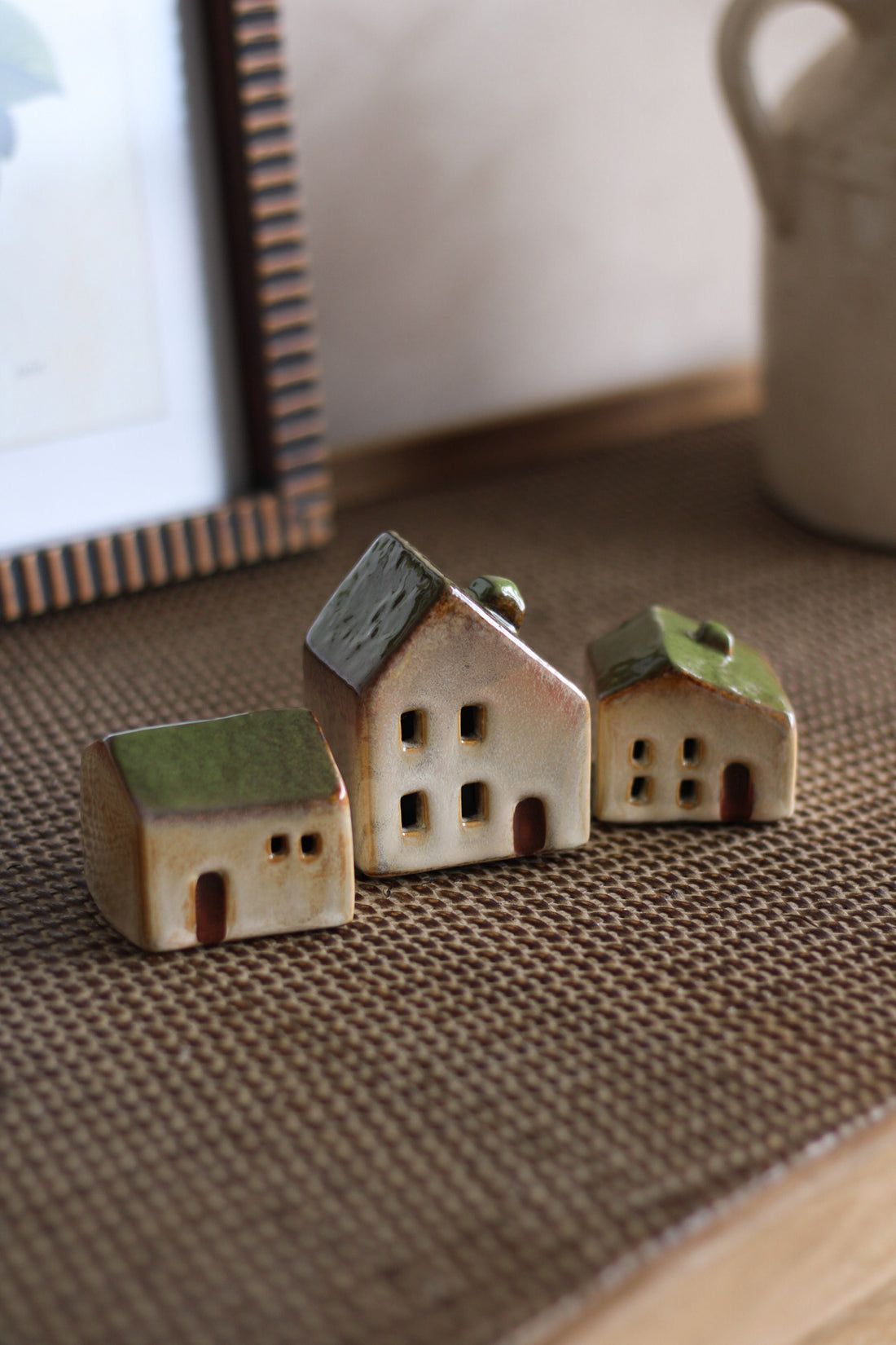 Three small ceramic houses on a textured surface with a blurred background