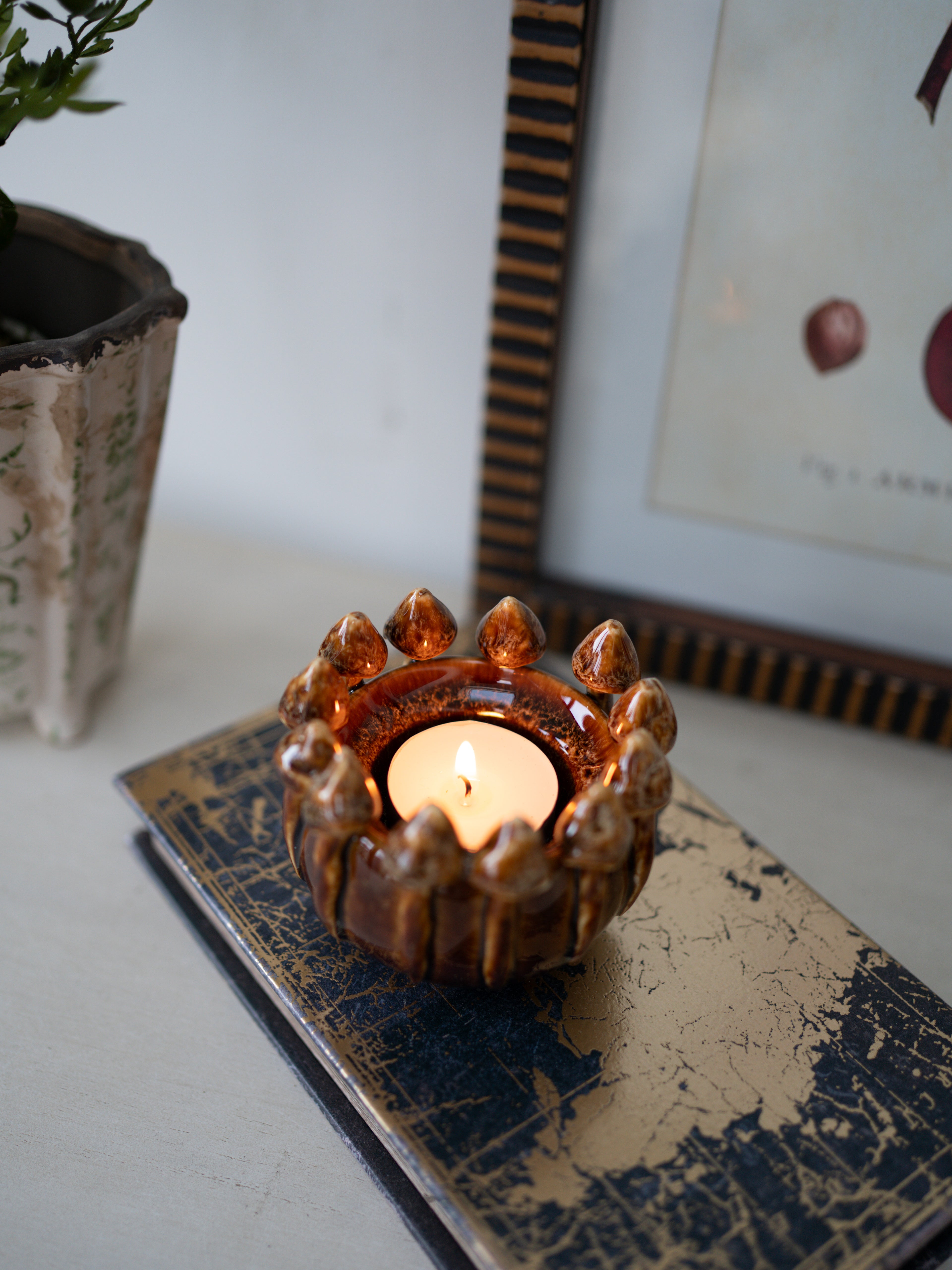 Decorative 3d effect brown mushroom candle holder with a lit candle on a textured surface