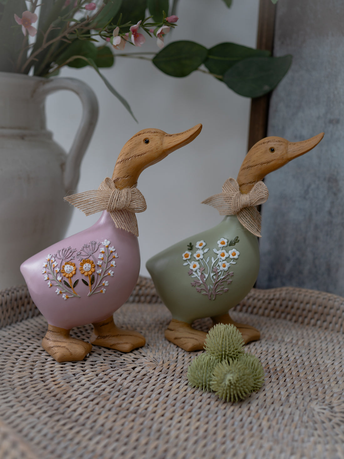 Two decorative ducks with floral designs on a textured surface.