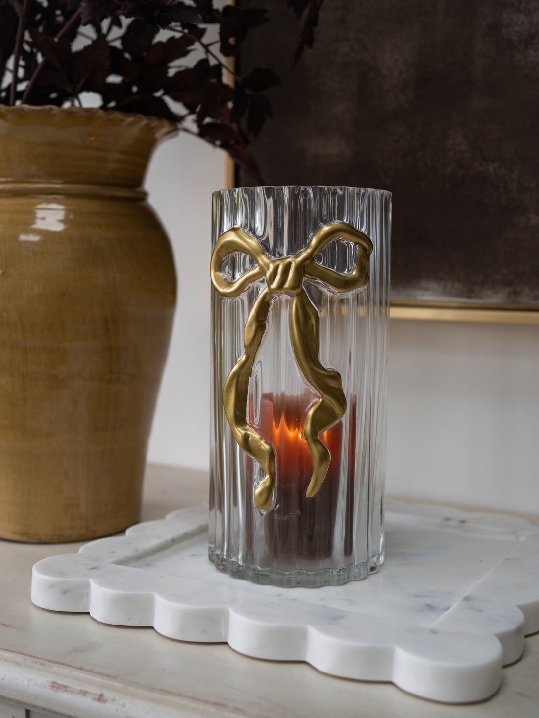 Embossed Gold Bow Candle Holder with ribbed glass jar on scalloped marble tray