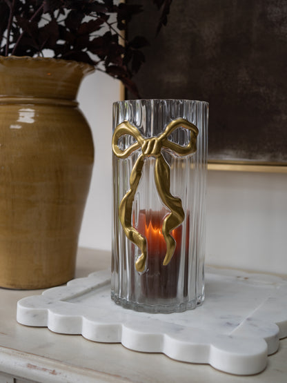 Embossed Gold Bow Candle Holder with ribbed glass jar on scalloped marble tray