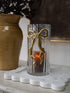 Embossed Gold Bow Candle Holder with ribbed glass jar on scalloped marble tray
