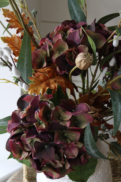 Bouquet of autumn flowers with purple and green hues in a vase.