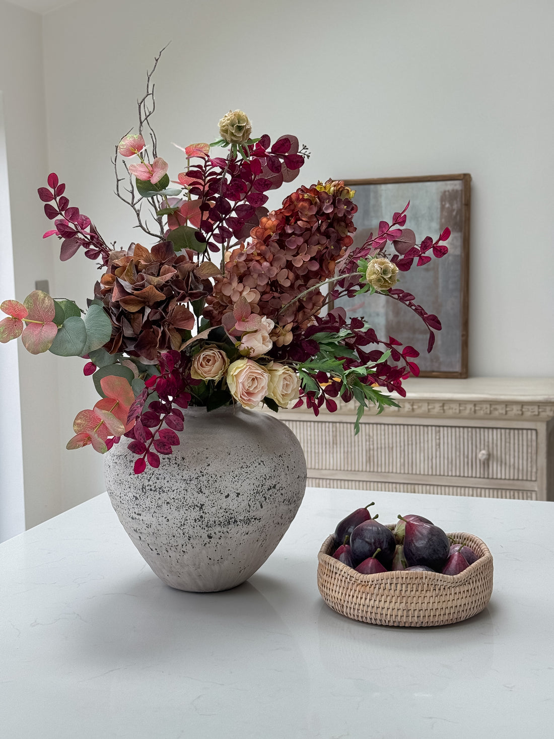 Decorative vase with faux autumn flowers on a table in a room setting